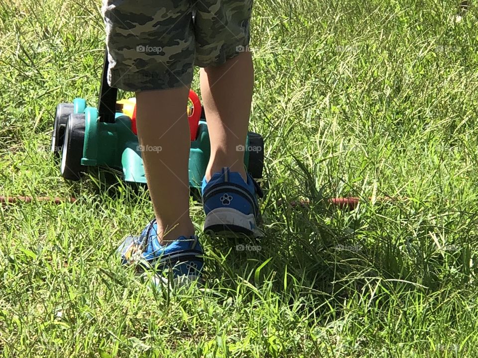 Sweet little boy plays with toy mower