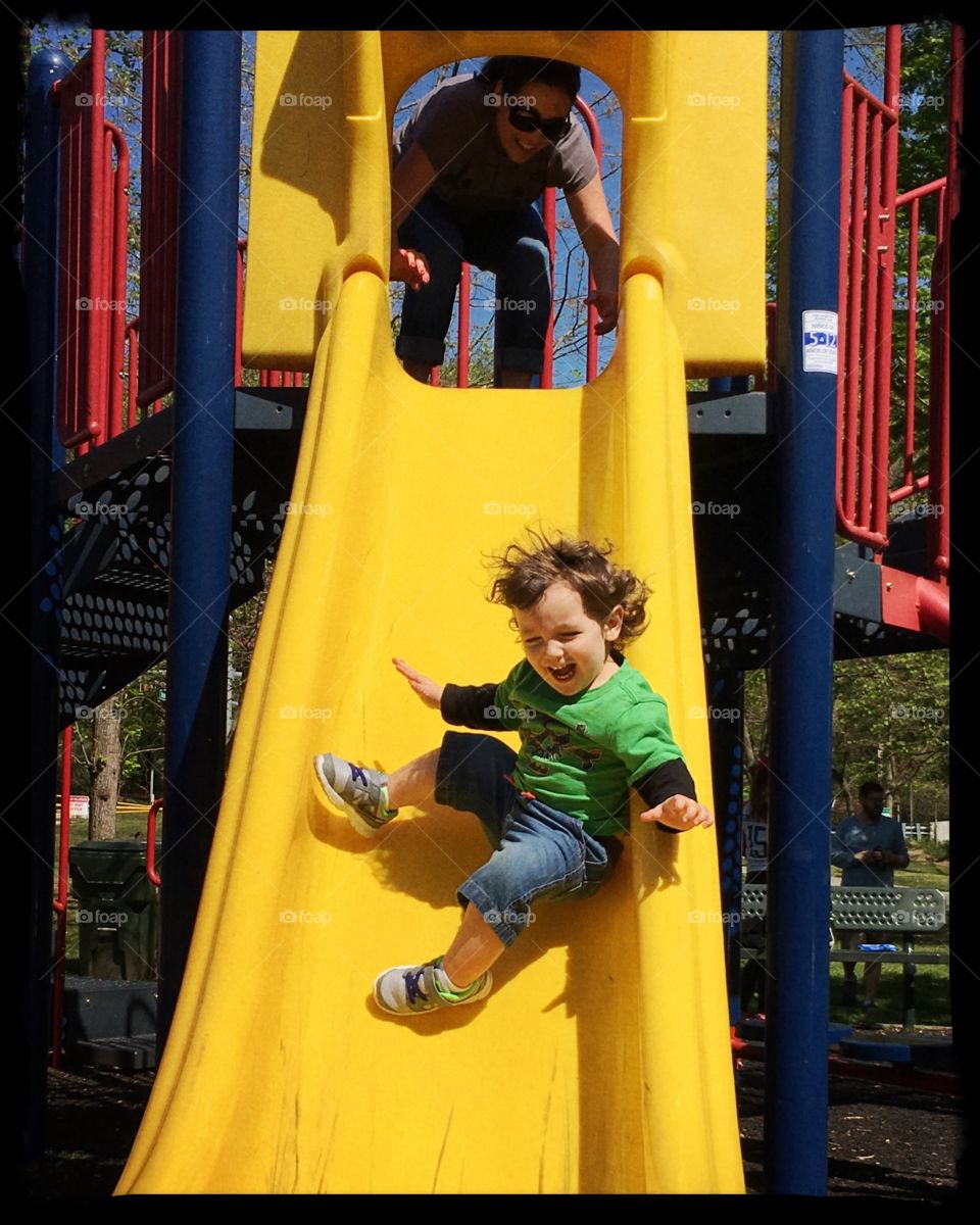 A child having fun sliding down a sliding board at a park 