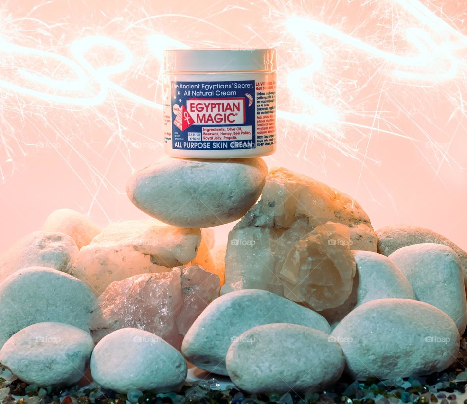 Egyptian Magic All Purpose Skin Cream position on a pile of assorted stones and a sparkling background 