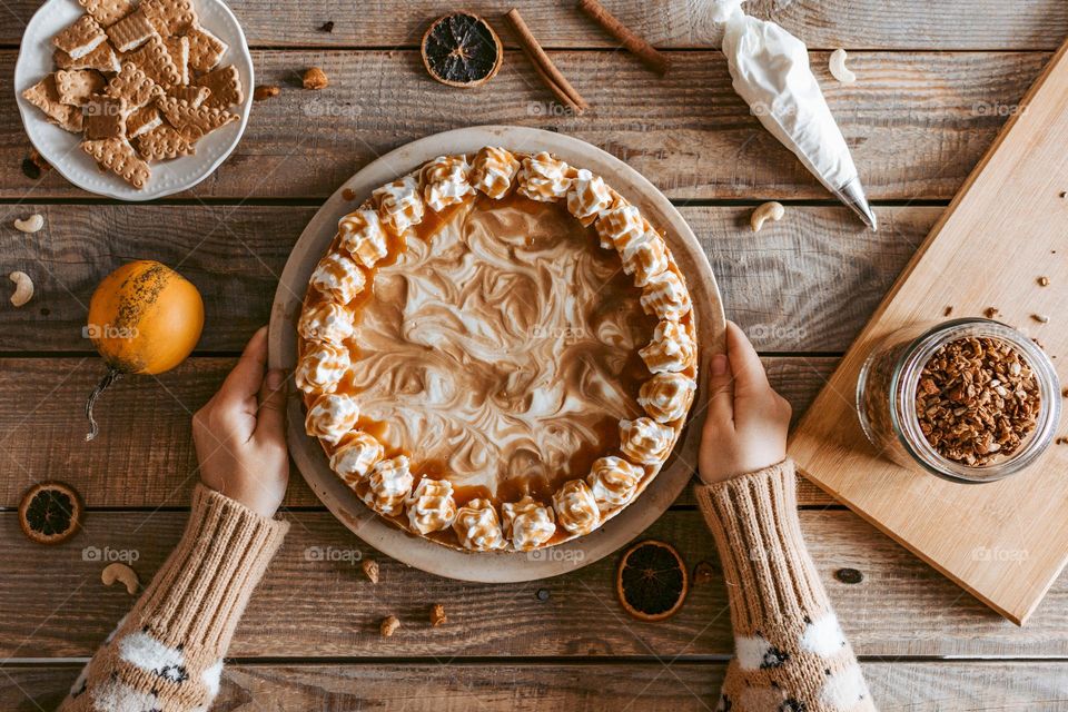 Top view of hands holding delicious cake on tray over wooden boards