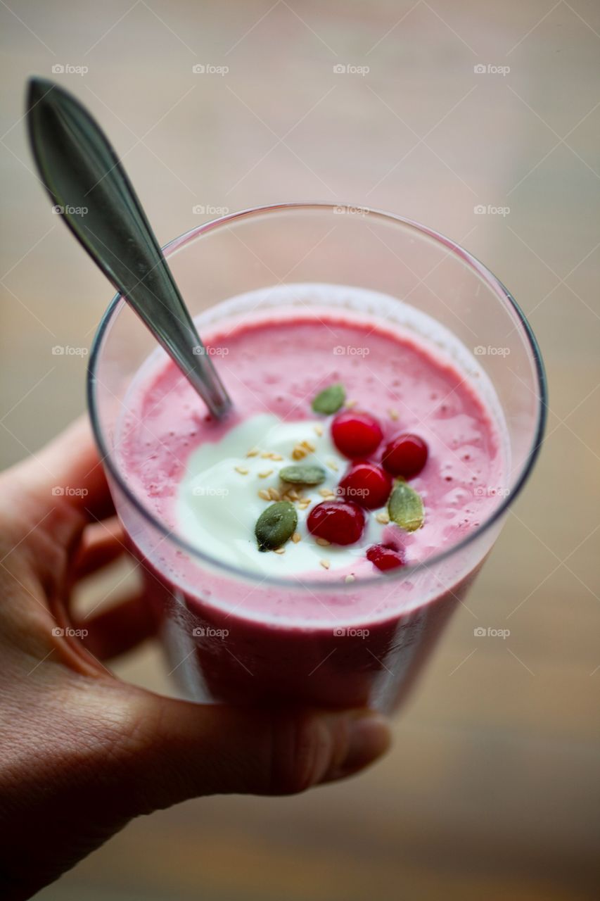 Hand handing raspberry smoothie