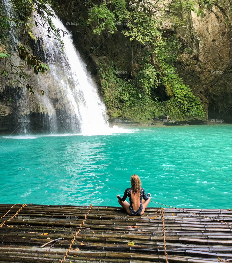 Woman sitting by the waterfall doing yoga