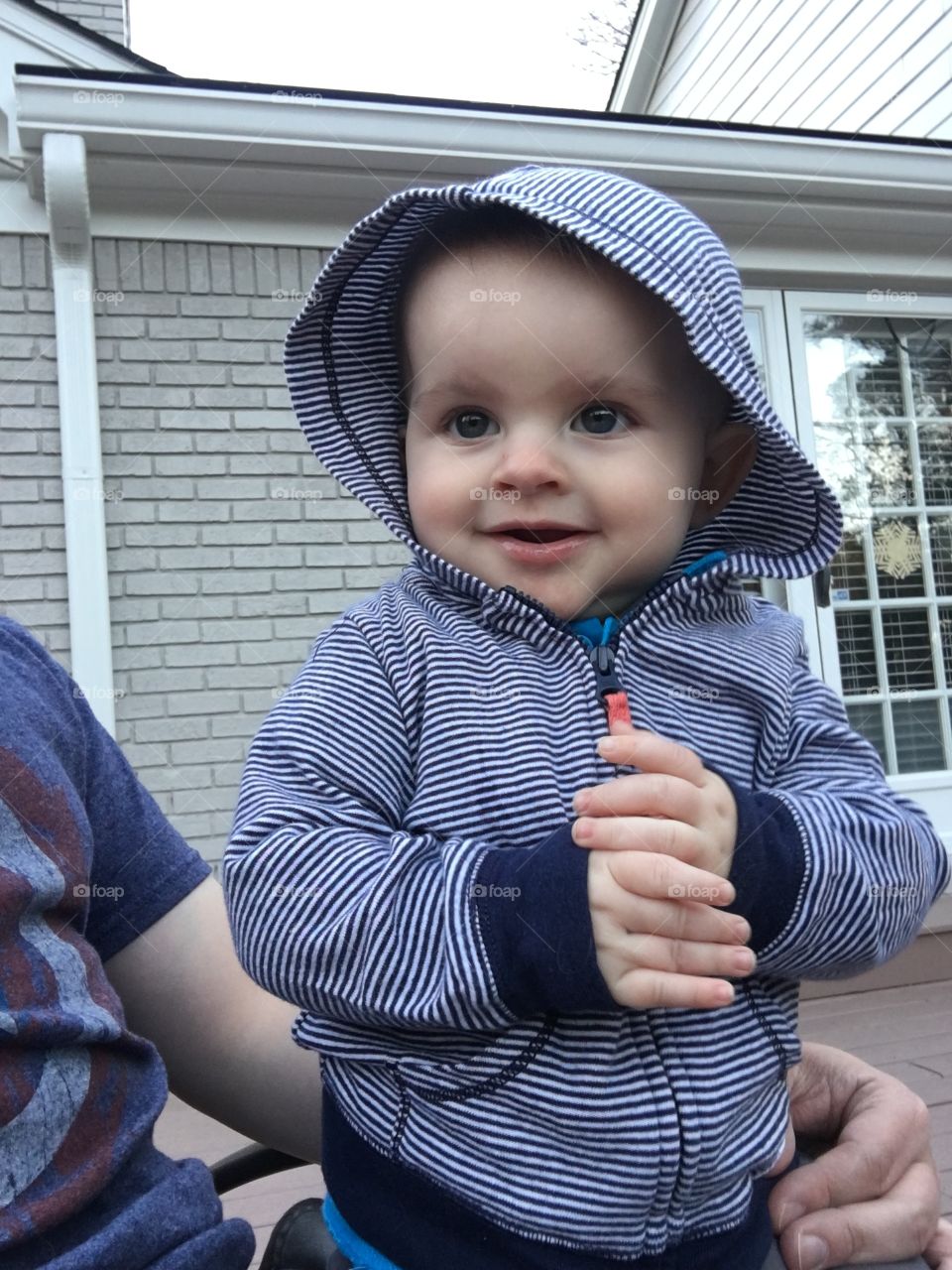 Baby boy sitting on back porch smiling.