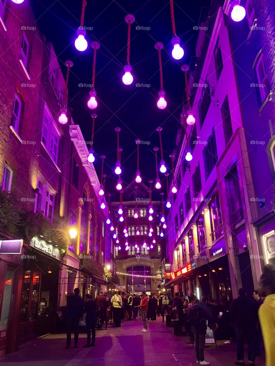 London, Carnaby street, under purple neon lights, crowded with people, nightlife 