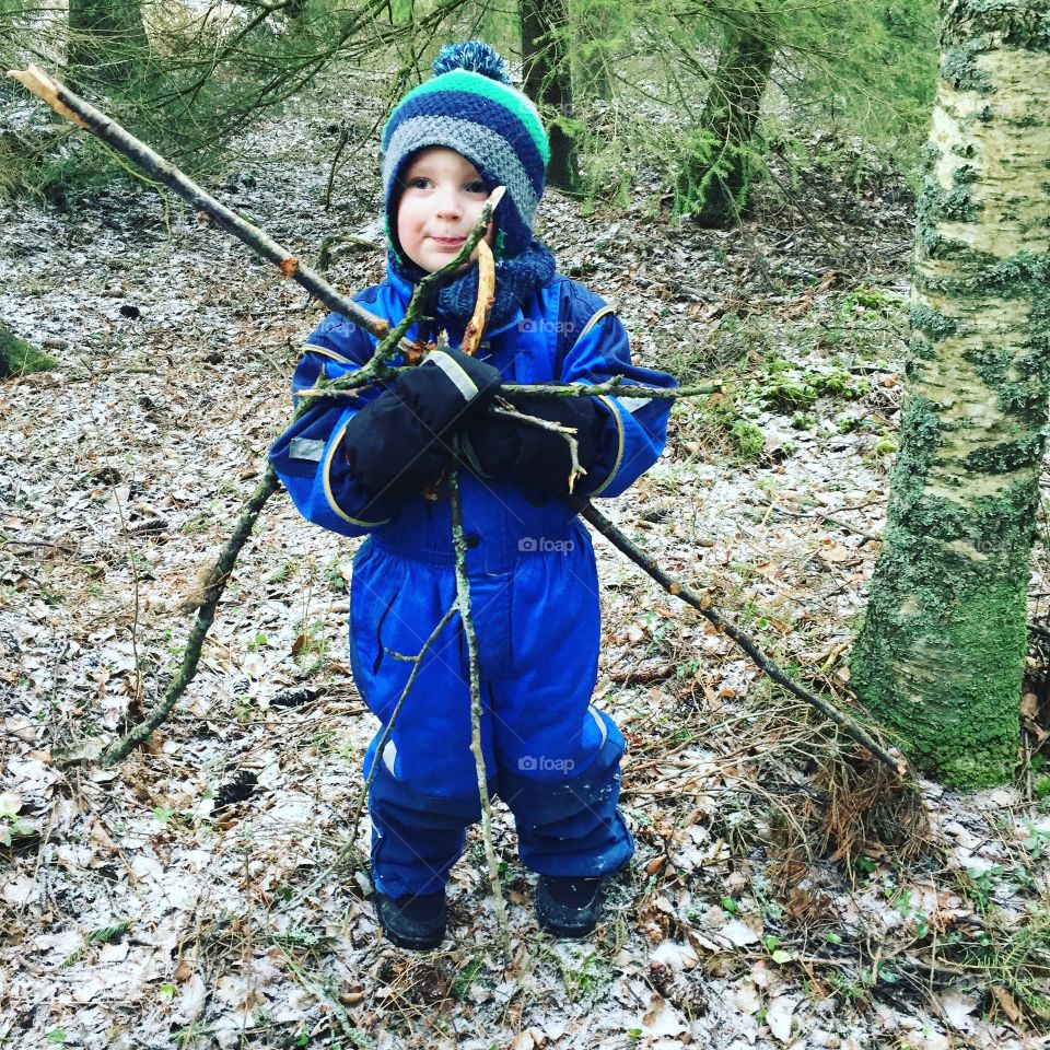 Small boy holding branches of tree