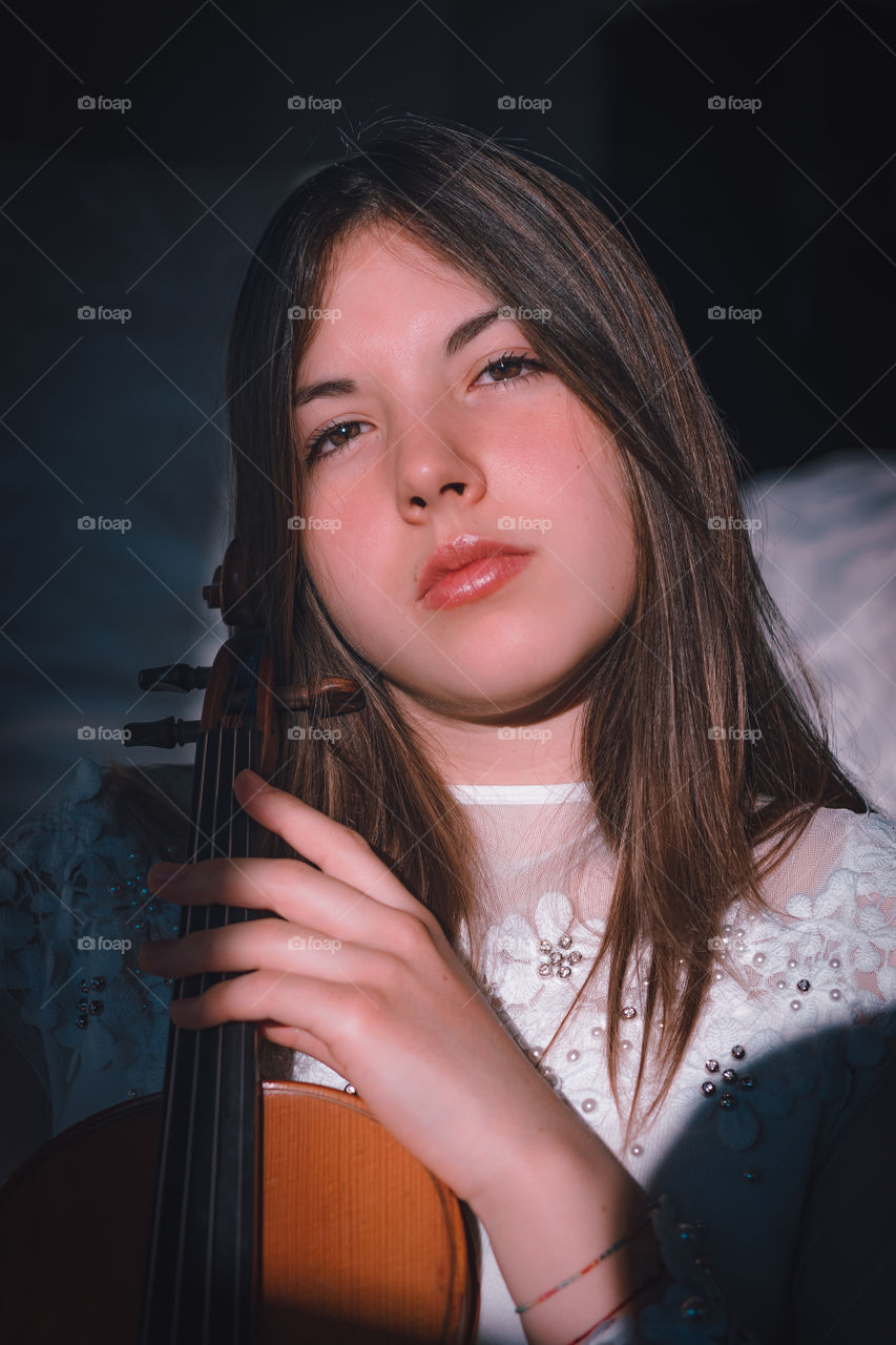 Girl holding a violin in the house