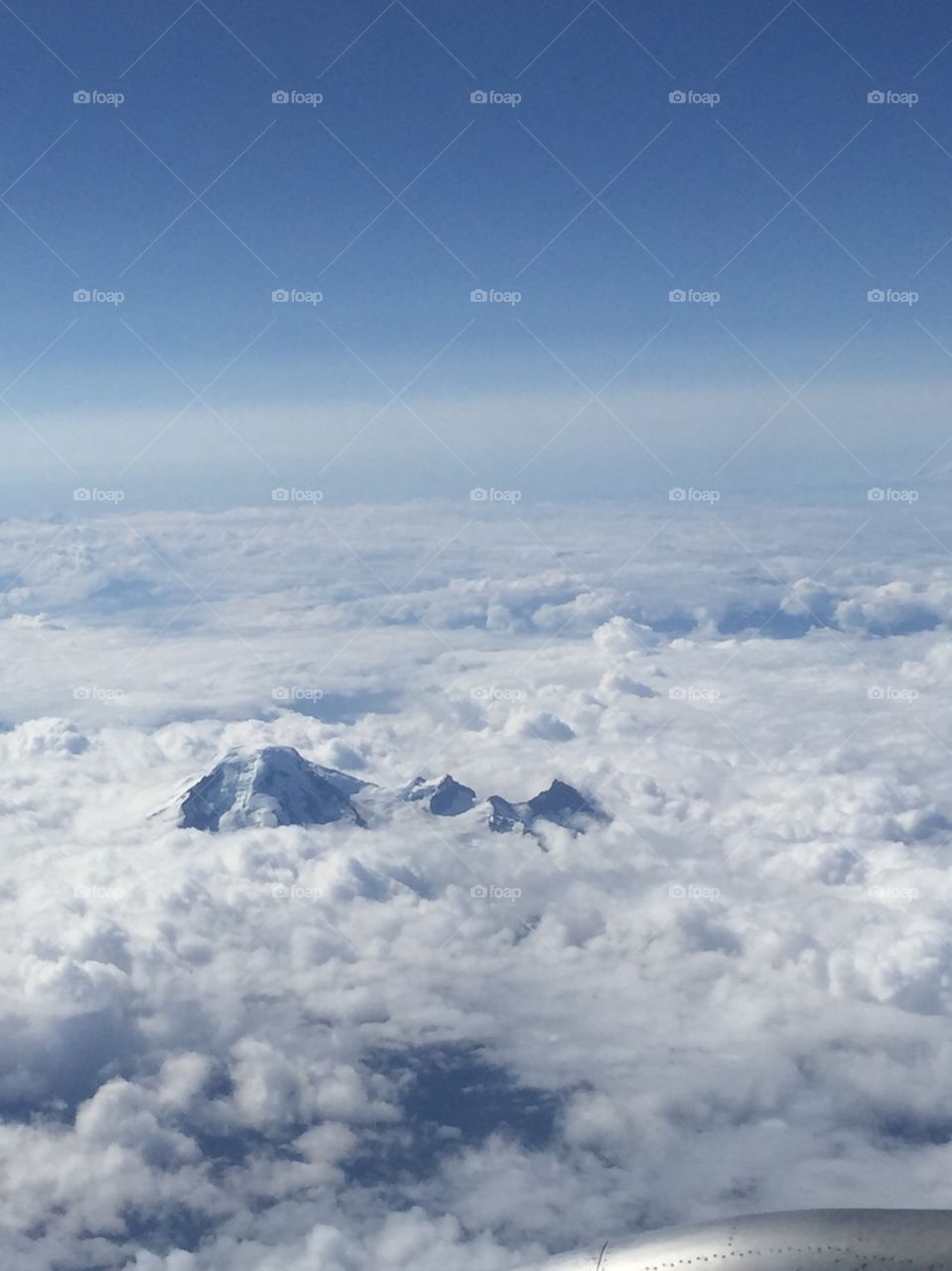 The tops of mountains are visible from a window on board a plane.