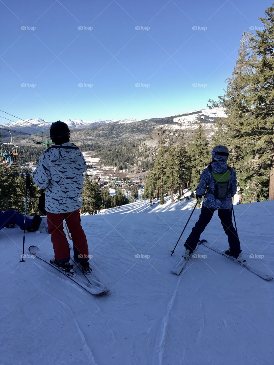 Two skiers at the top of a snow covered slope