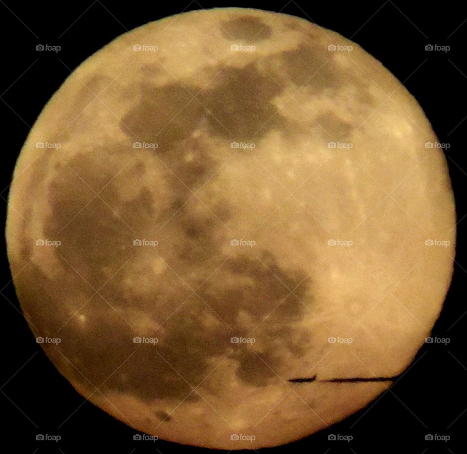 Plane Moon. A distant plane crossing in front of the rising full moon