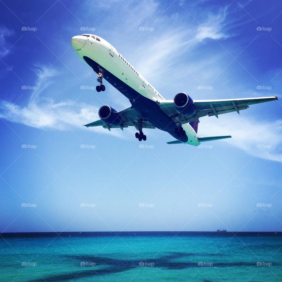 Summertime travel, traveling on a plane, plane flying over a beach, Maho beach In St. Maarten 