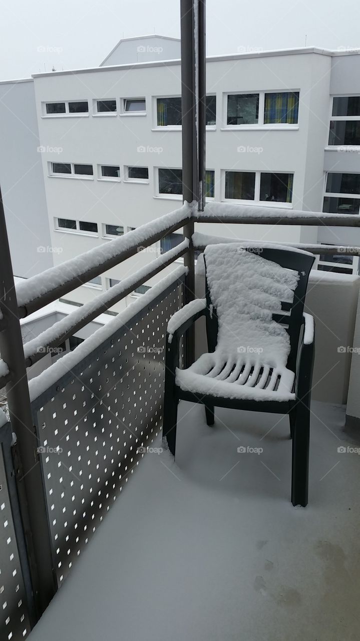 Stuhl verschneit auf dem Balkon