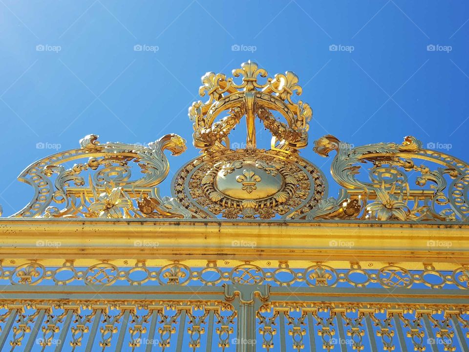 versaille palace paris front gate gilded in gold with french royal family emblem and coat of arms