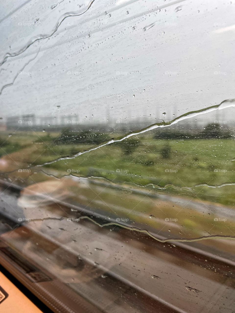 View of the landscape from a train window in the rain
