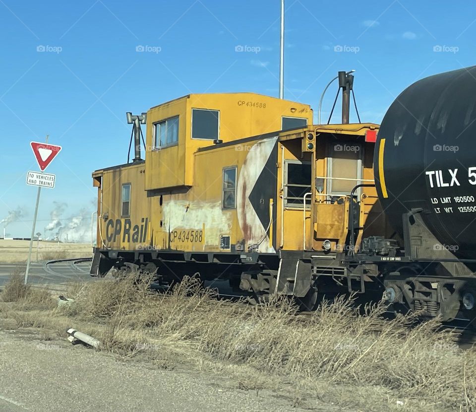 I love yellow caboose trains the most, cause it means traffic can start moving again, this one is part of CP Rail and has graffiti on it, on a calm winter sunny day, with no snow