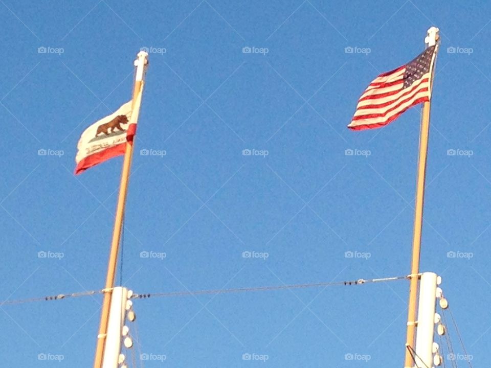 California state flag & US flag against a cloudless blue sky