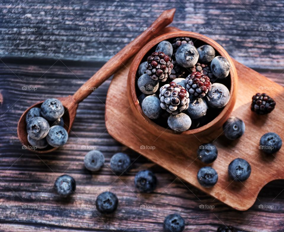 Blueberries and blackberries in wooden bowl