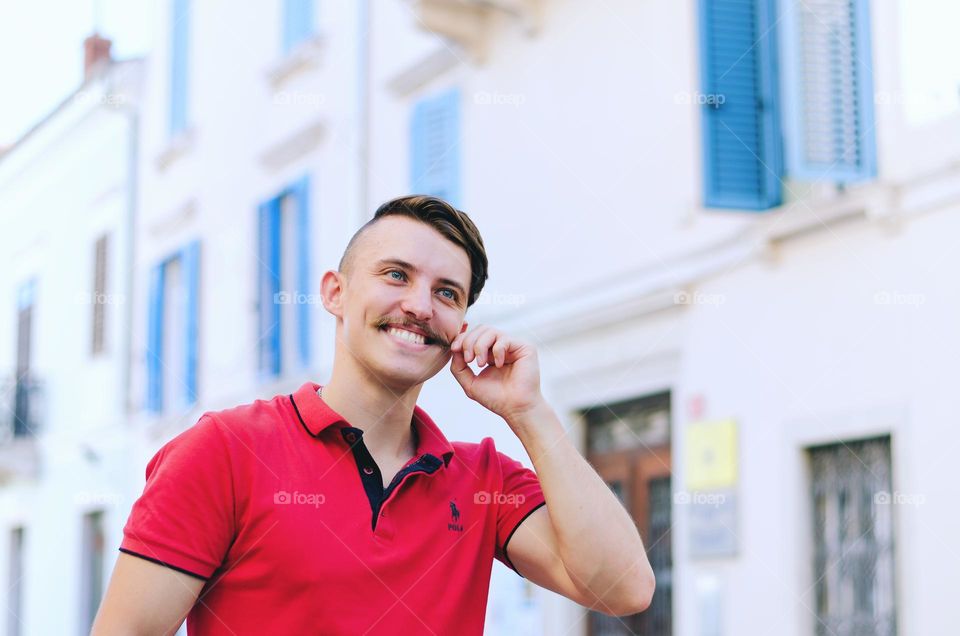 Young happy handsome bearded man, tourist in sunglasses. Guy walking in old city of Koper,  Slovenia