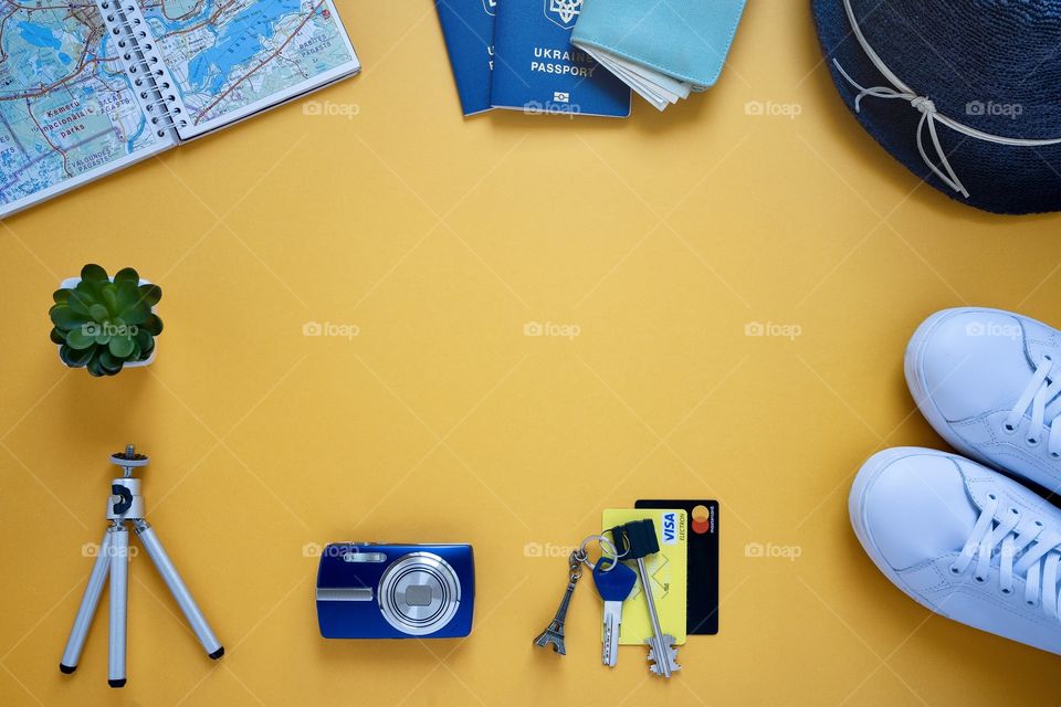 blue hat, passports, blue camera, money wallet, keys, white shoes, map, credit card, things on vacation on a yellow background, top view