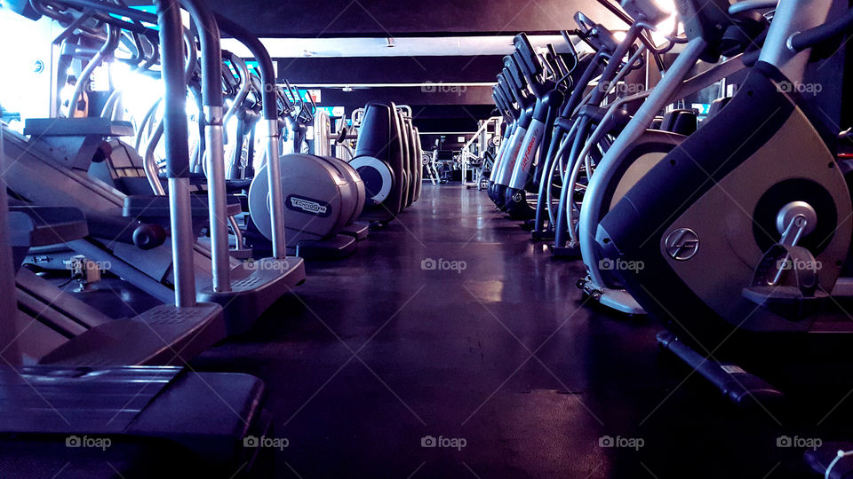 Esta es una fotografía de un gimnasio para invitar a la gente a inscribirse la maquinaria que se ve son maquinar para hacer ejercicio cardiovascular para bajar de peso