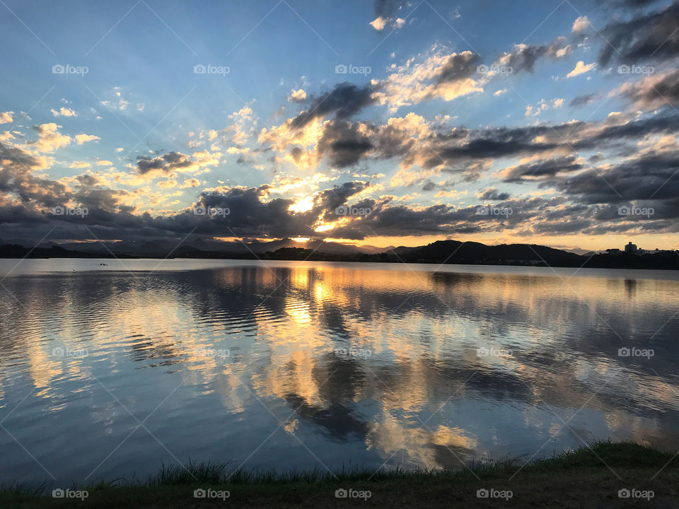 An amazing sunset viewed from the lakeside. It is possible to see the reflection of the sun's rays on the lake water making a beautiful spectacle