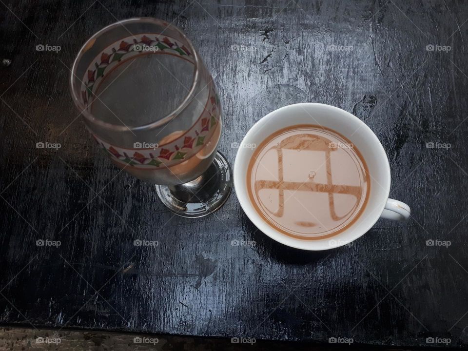Artistic design of how to pour mocha coffee between 2 glasses on a black wooden table