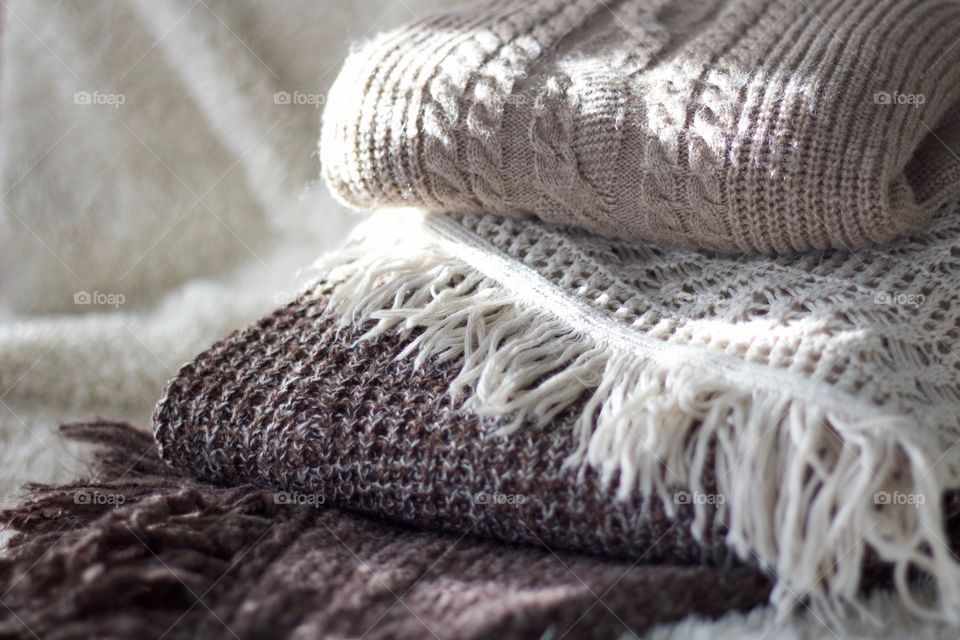 Cable knit, crocheted and fringed sweaters in taupe and brown on a sheepskin throw 