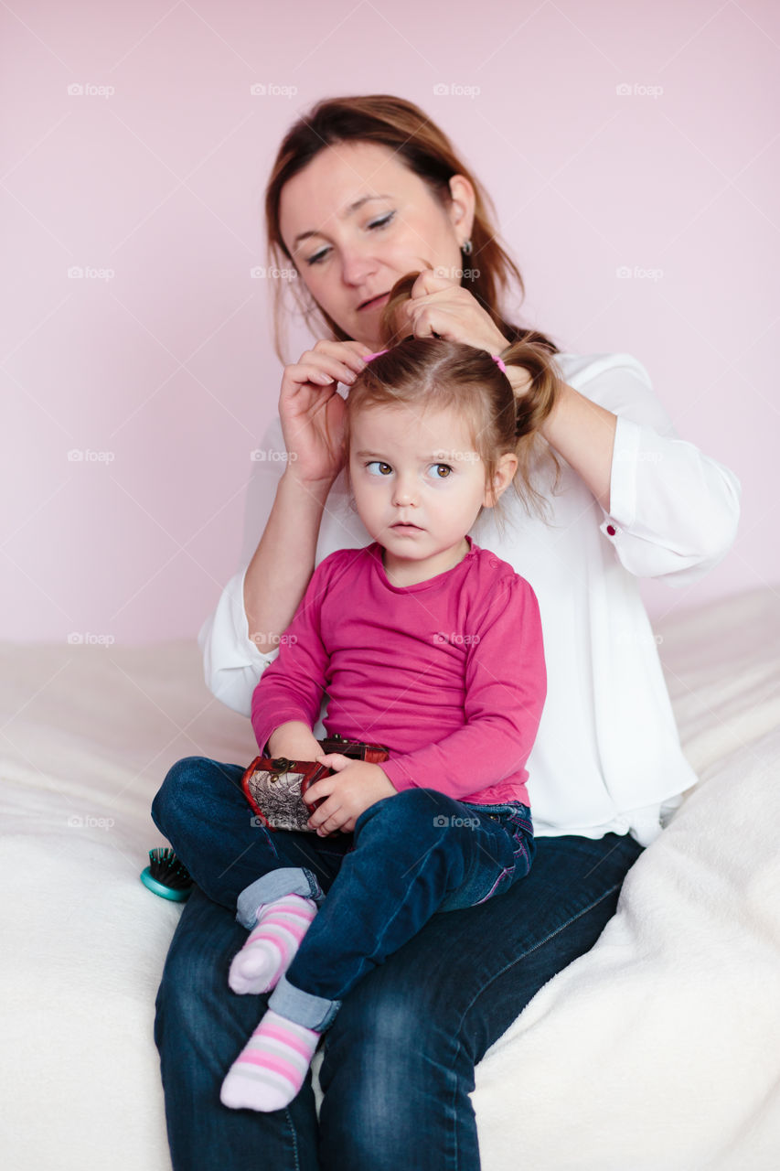 Portrait of mother tying pony tail on girl