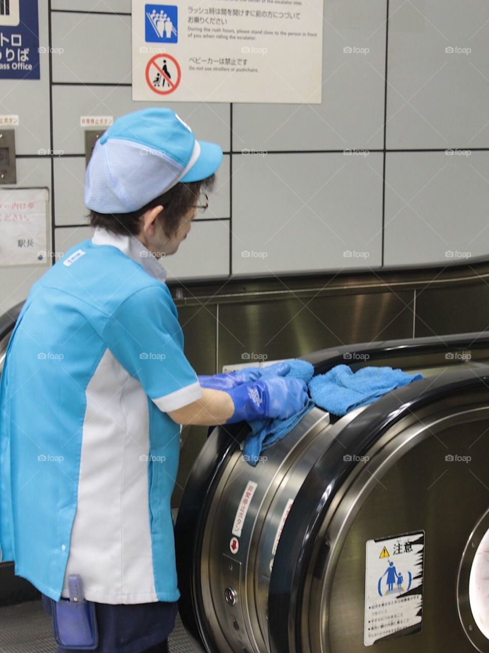 Japanese woman cleaning escalator handrail 