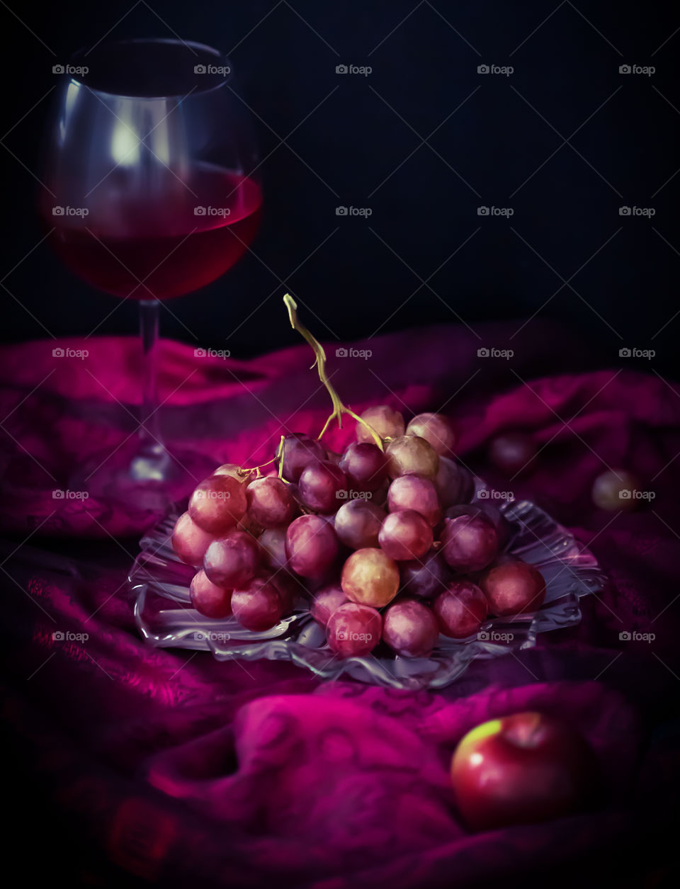 A slightly blurred still life with a glass of red wine, grapes and apples. Homemade red wine and its tasting. Concept of healthy food and seasonal fruits. Food photo, vertical orientation