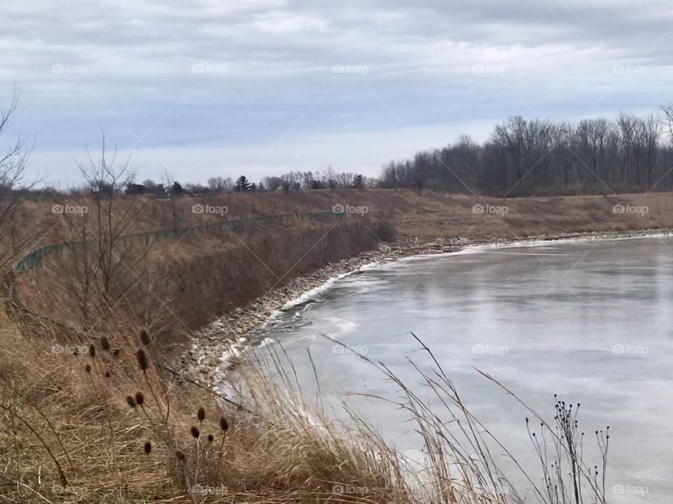 A frozen over creek contrasted with a dusk sky. 