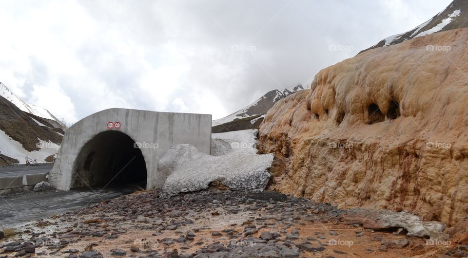 Road to the Cross Pass in May. Avalanche tunnel and mineral water source
