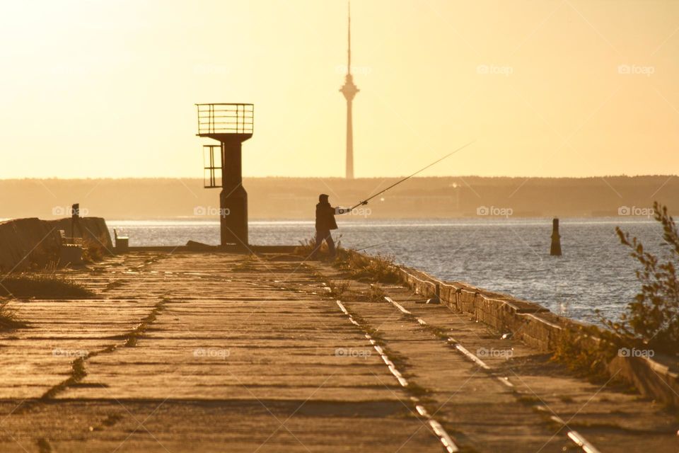 Fisherman in the early morning by the sea at sunrise.