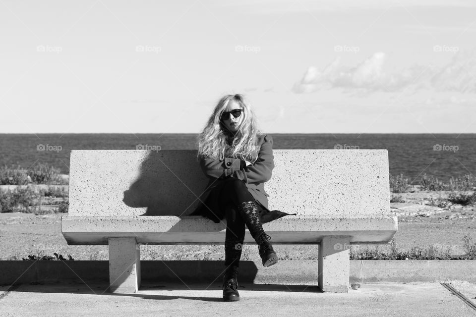 Portrait of a woman sitting on bench near sea