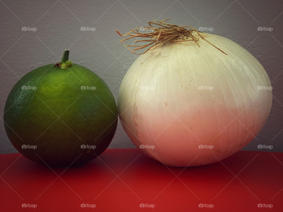 A white onion and a lime on a red table