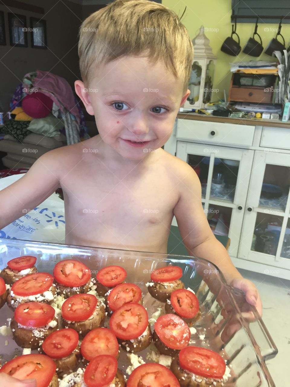 Cute boy holding tray of stuffed potatoes in hand