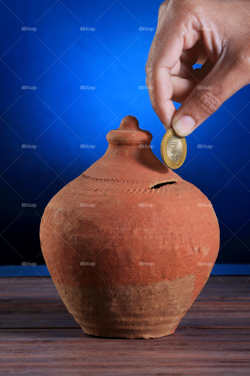 Indian handmade pottery Piggy bank with coin in a hand