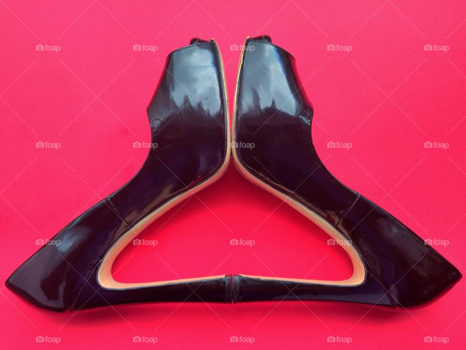 Triangles.  Black shoes lie on a red background.  The heels of the shoes form a triangle
