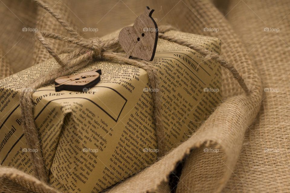 close up gift box with hearts and space for text on sackcloth background.