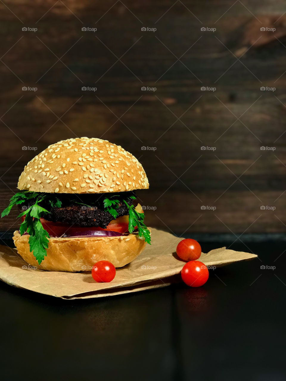 delicious hamburger with bun, served on the board with a small red cherry tomatoes