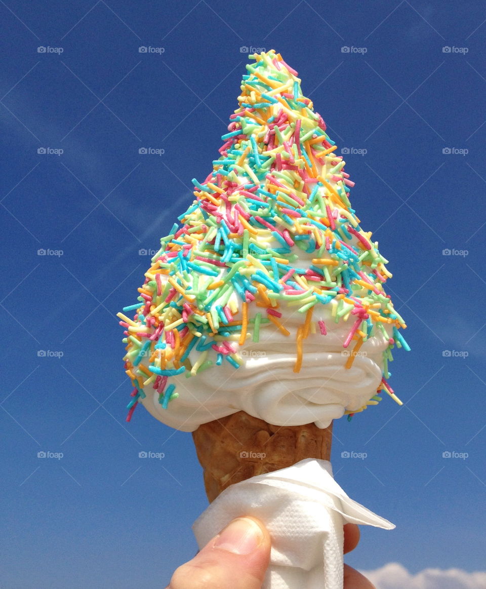 Hand holding ice cream cone with sprinkles