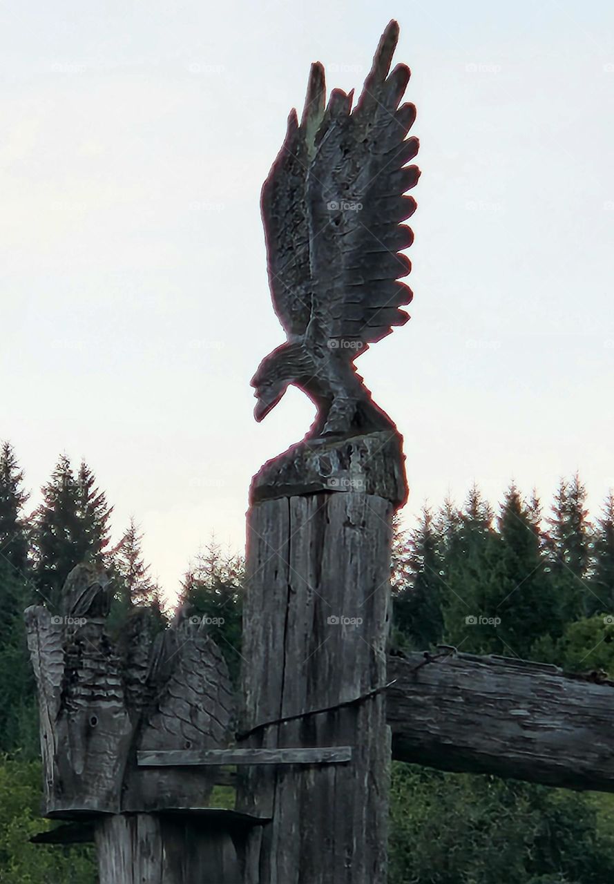 carved wooden eagle totem post taking flight among the trees at the entrance to a popular restaurant in Oregon