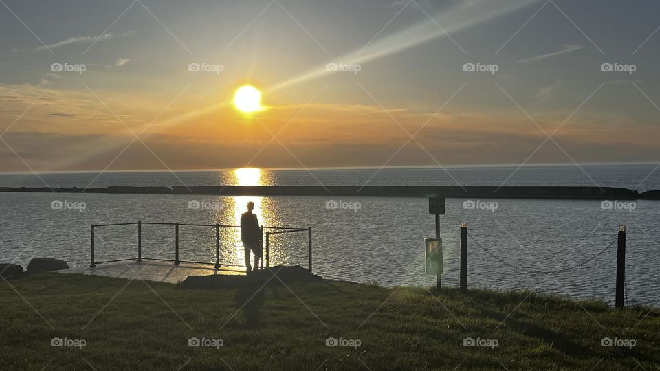 enveloped by the light of the setting sun, they have become one. my fiancé was embraced by the sunset over lake Ontario❤️