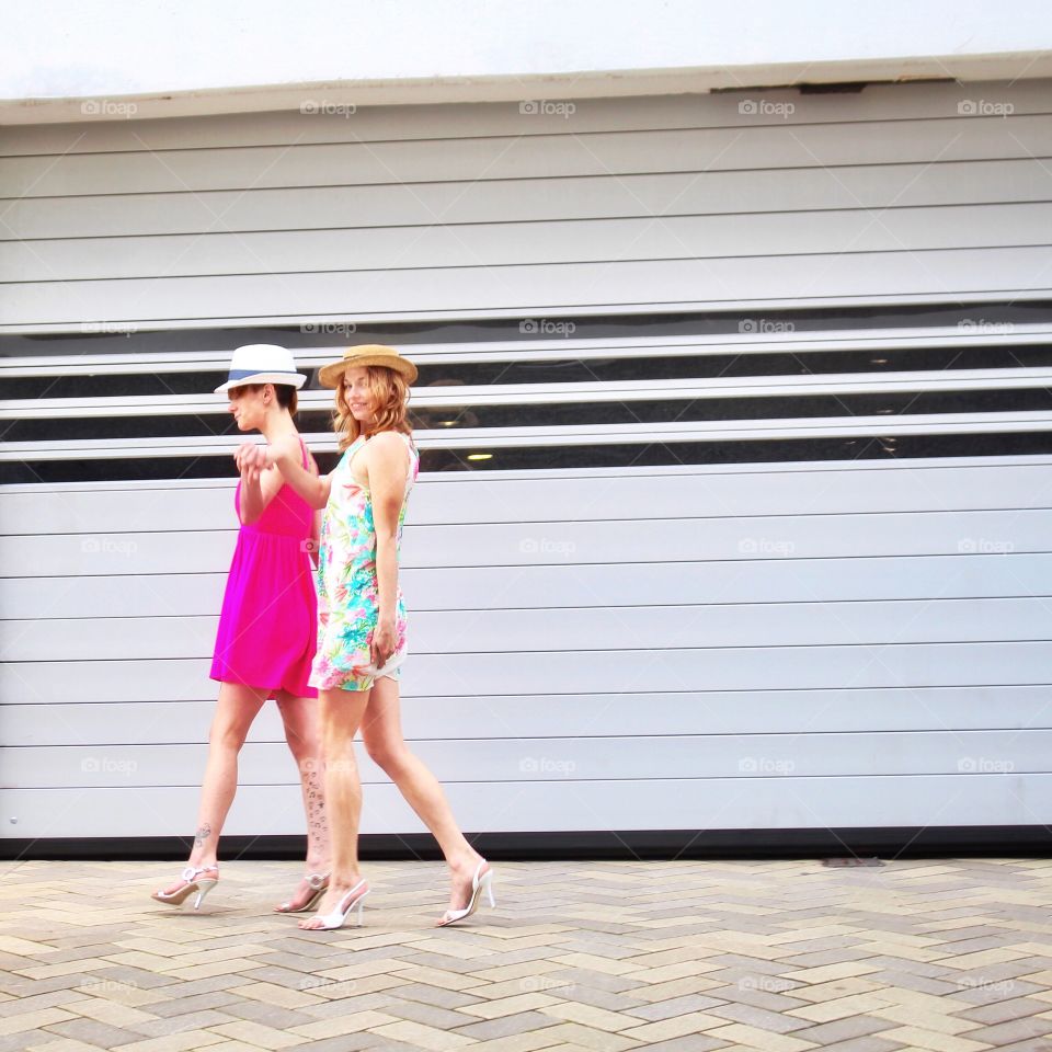 Two young millennial girls out for a stroll on a warm sunny spring day in front of a white and black industrial architectural designed wall in an urban setting!