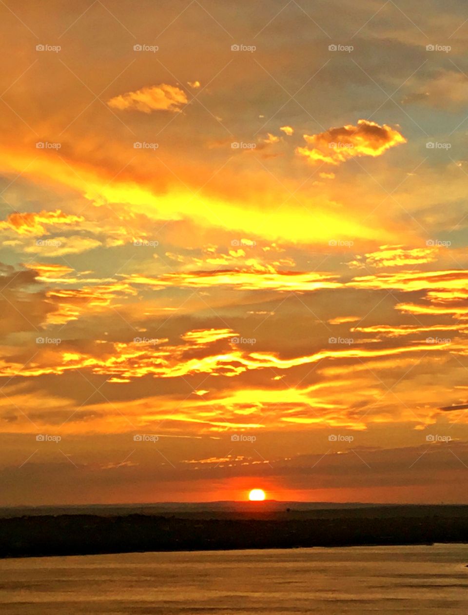 Golden Sunset - A visual orange sun descending below the horizon leaving behind a sparkling gold colored sky
