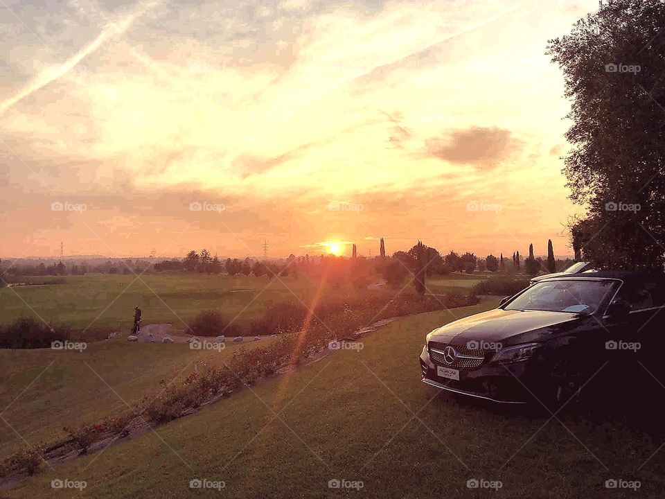 Spectacular sunset at the golf course, with Mercedes cars on display, during an important international event.