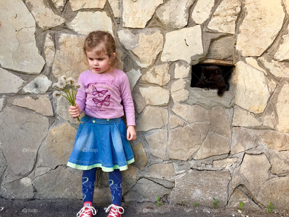 Cute girl standing at the wall with black cat 