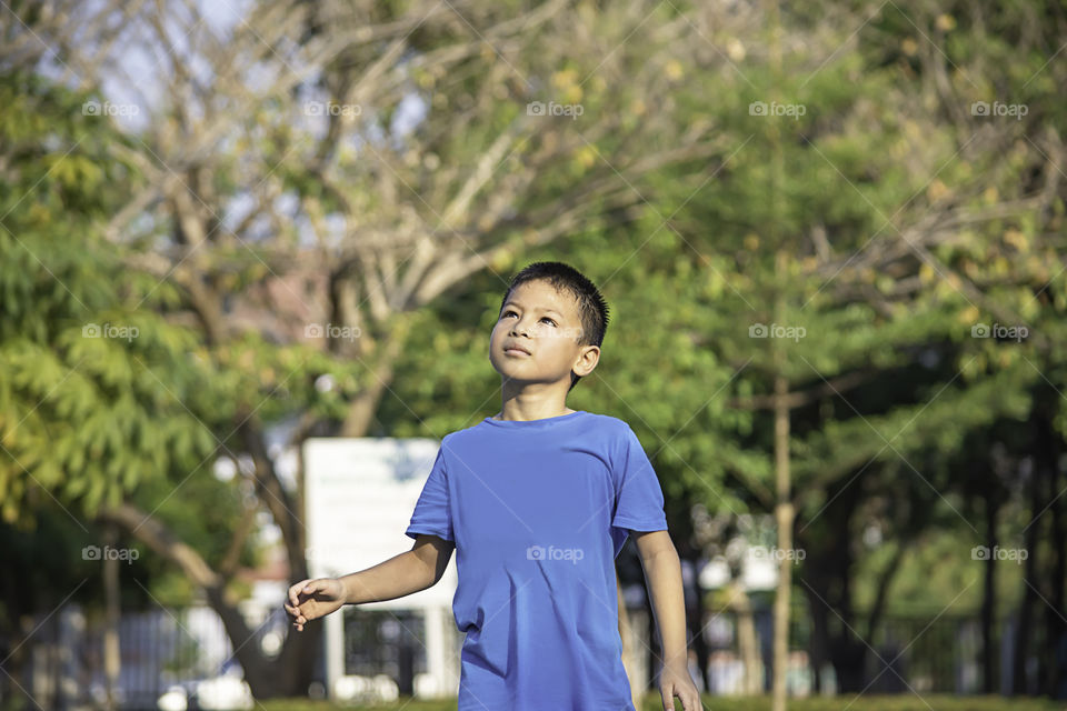 Portrait of a boy Asia laughing and smiling happily Background blurry trees in park.