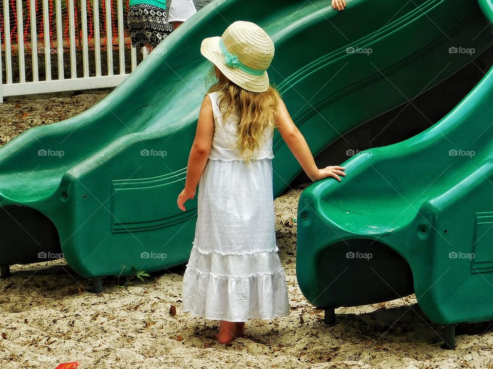 Rear view of girl standing near slide