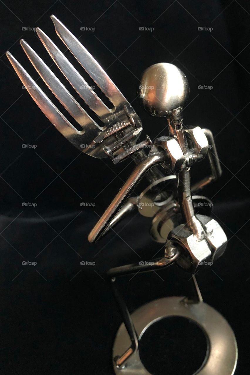 Mr. Forkman not ordinary metal man sculpture holding a fork viewed from behind silver chrome