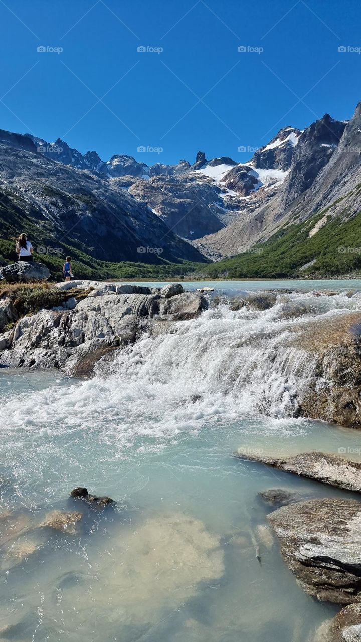 light blue lagoon sourrounded by mountains and blue sky